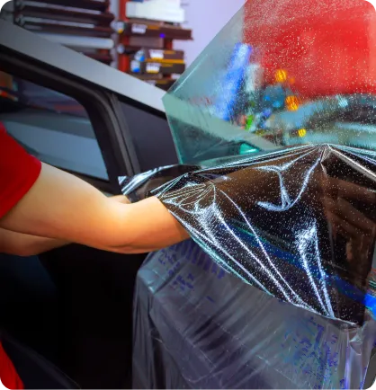 Película sendo instalada em um dos vidros de um carro em uma oficina referenciada em instalação de película automotiva.