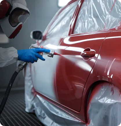 Lataria de um carro sendo pintada de vermelho por um prestador de serviço através do serviço automotivo de pintura automotiva.