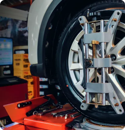 Roda de um veículo que está em cima de um elevador automotivo onde está sendo realizado o serviço automotivo de revisão do carro.