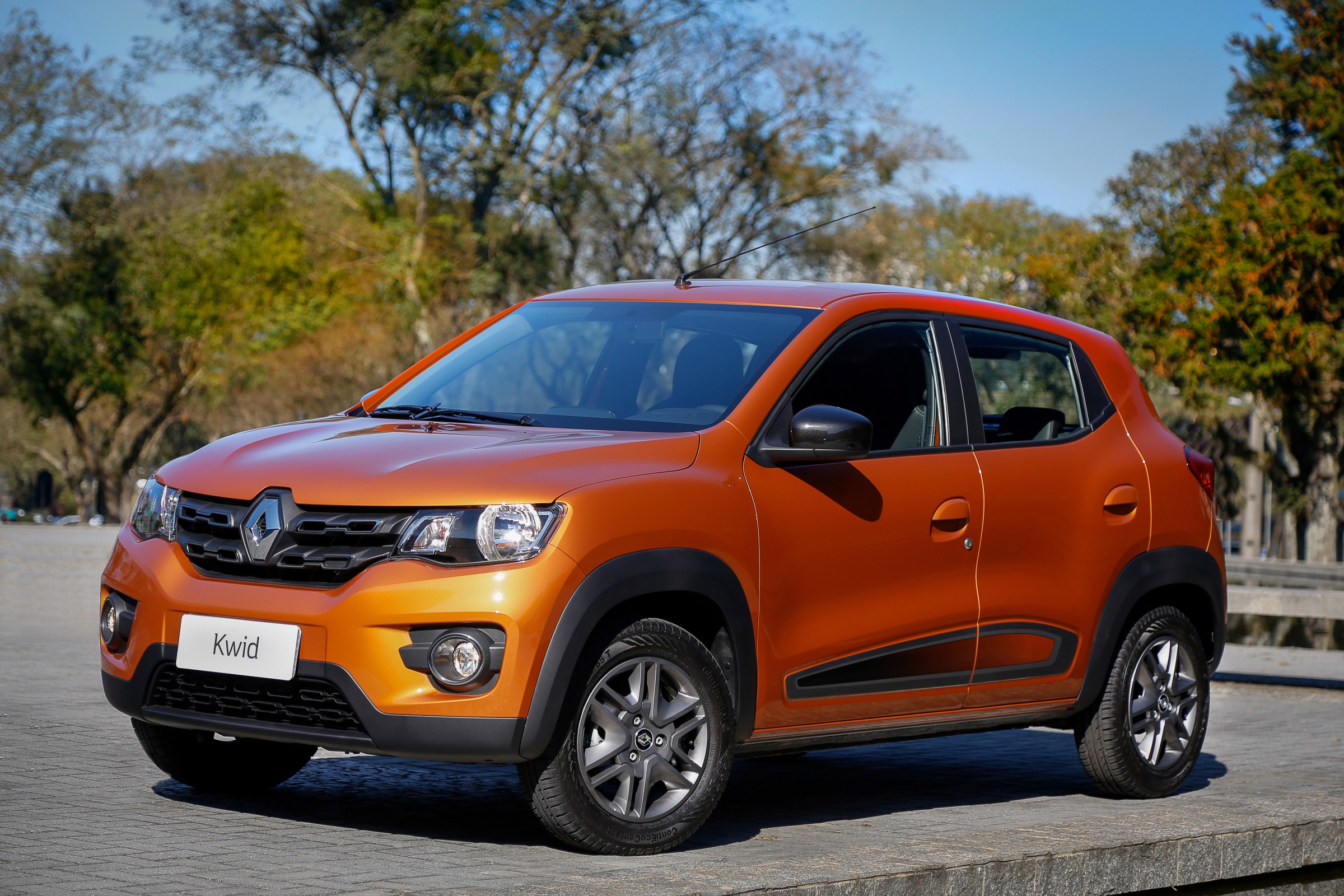 Renault Kwid Intense laranja na estrada com árvores ao fundo