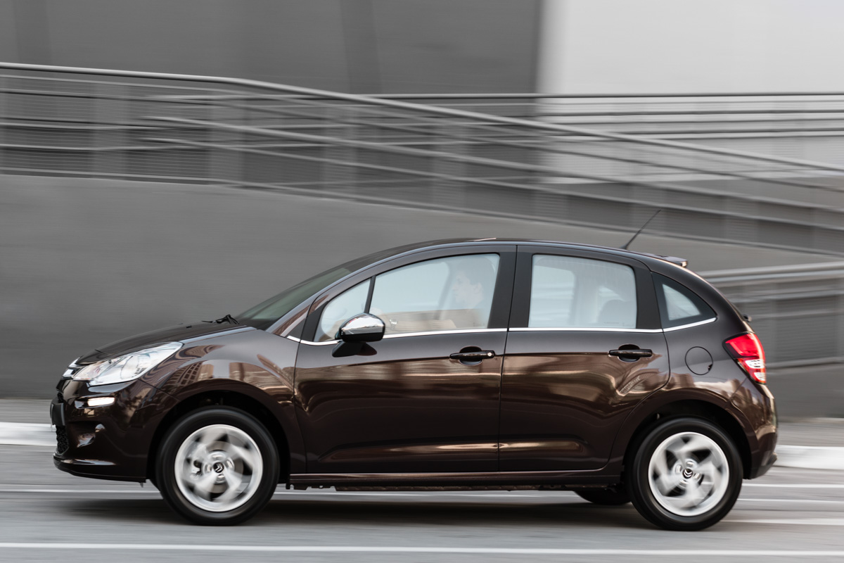 Citroën C3 marrom andando na cidade com paisagem desfocada ao fundo
