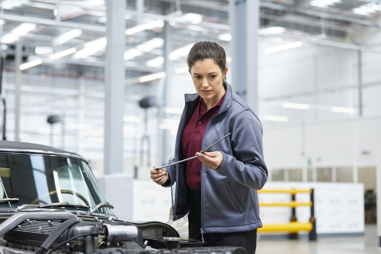 Engineer Checking Oil With Dipstick By Car