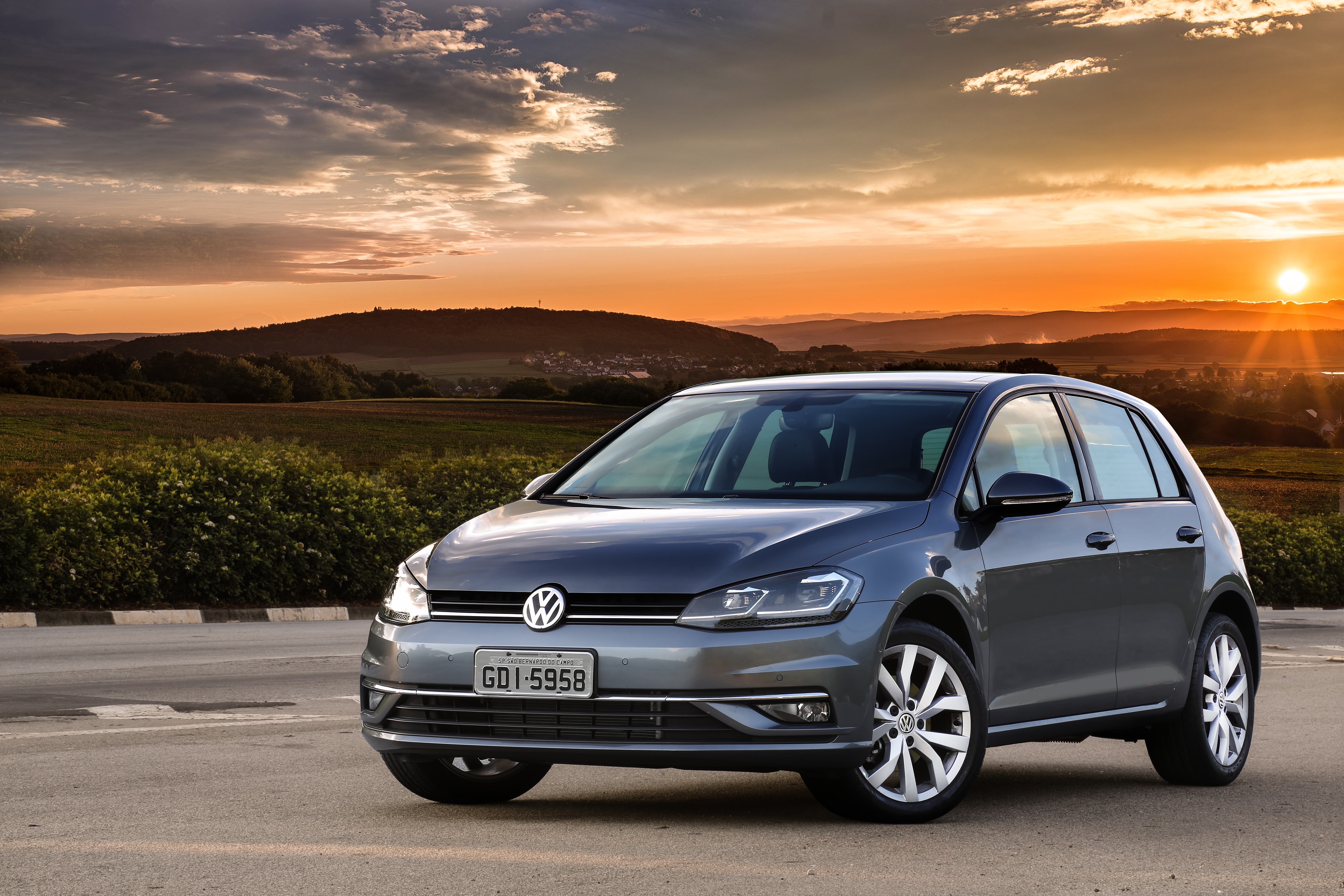 Volkswagen Golf Highline estacionado em estrada com por do sol ao fundo