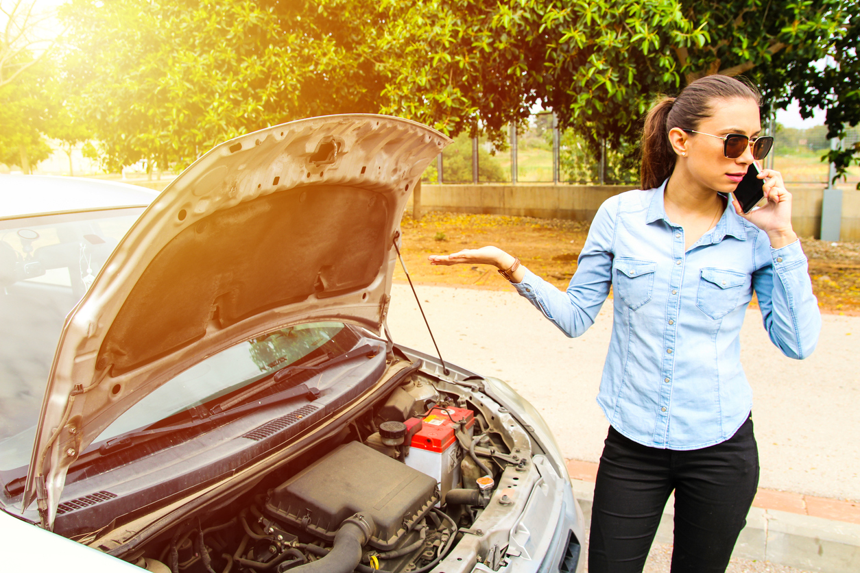 A Woman Talking On The Phone With A Broken Car