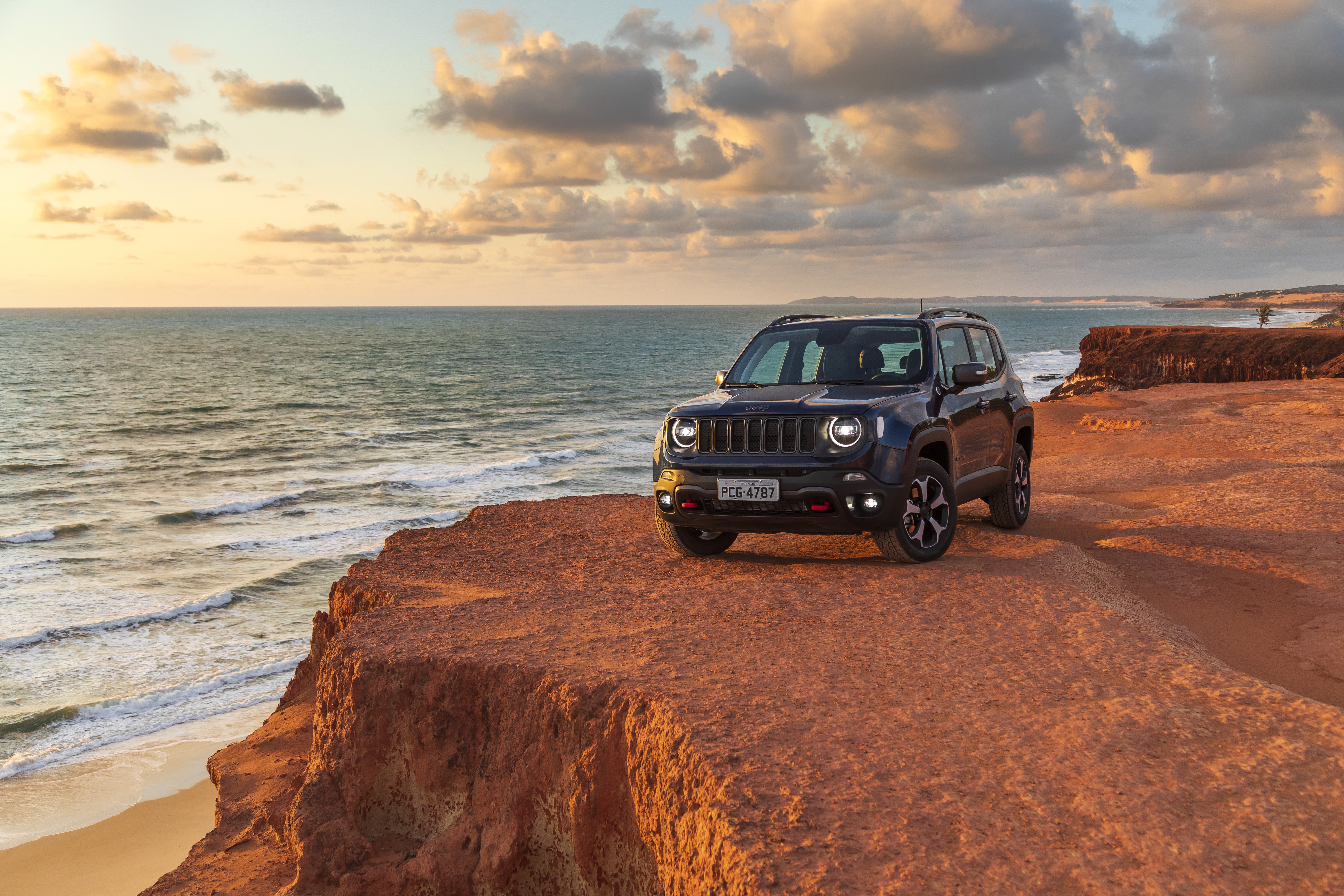 Jeep Renegade Trailhawk na cor azul no alto de um penhas tendo ao fundo falésias e o mar