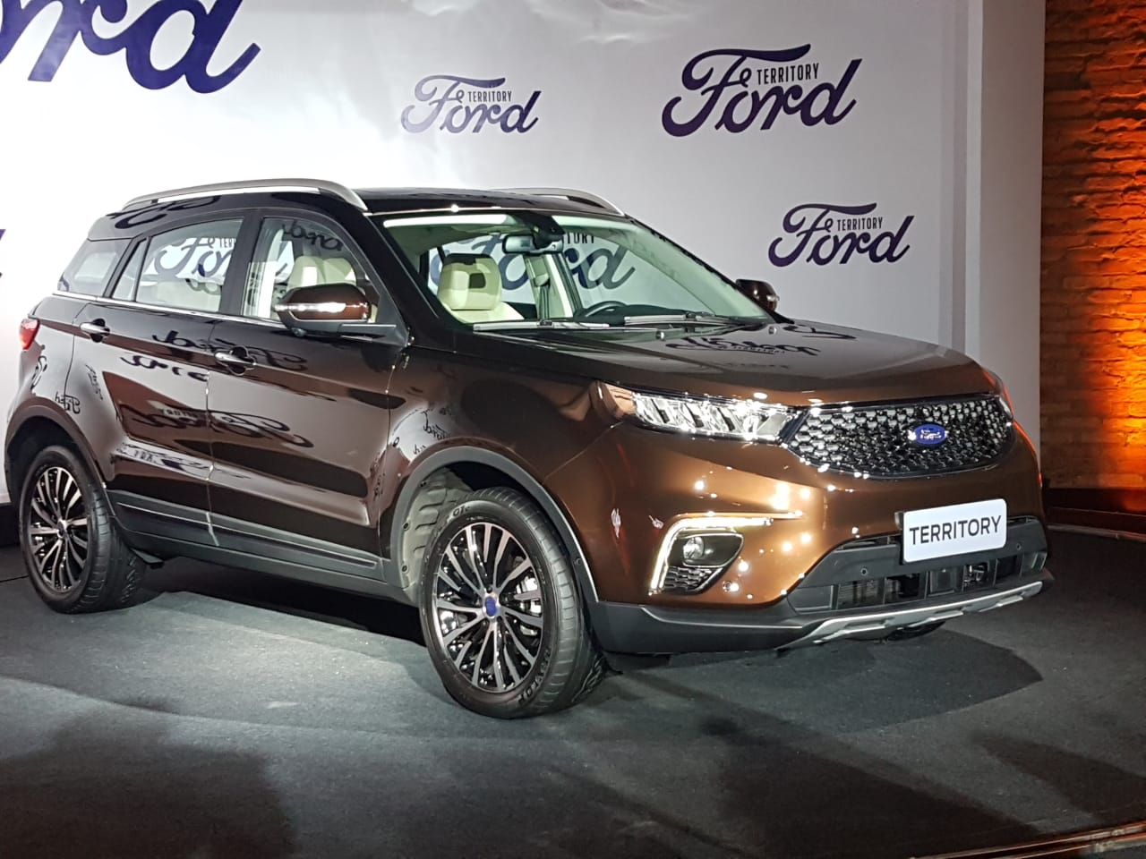 Ford Territory na cor marrom tem porte quadradão de utilitário esportivo, grade do tipo colmeia e faróis espichados