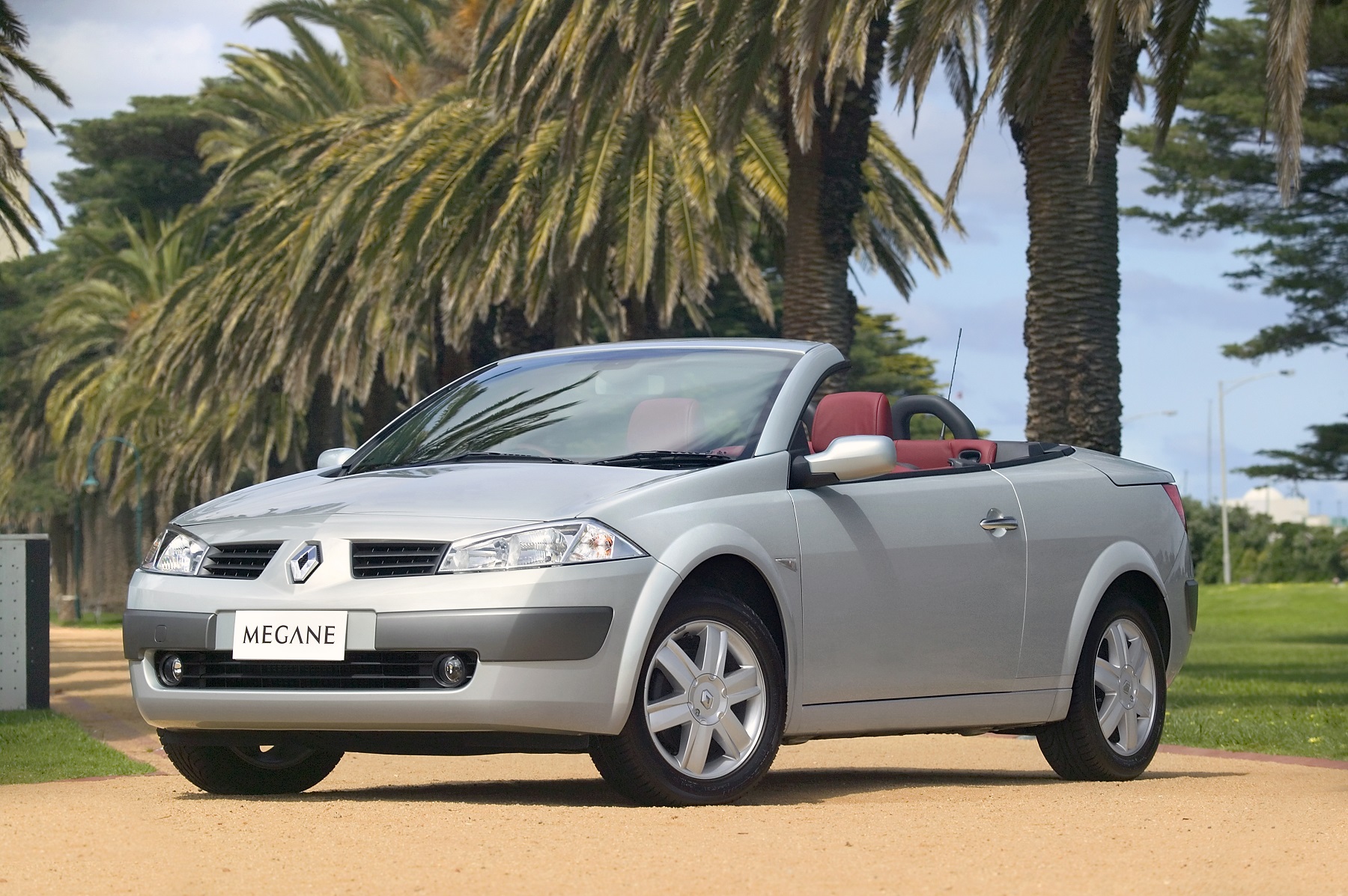 Mégane coupé cabriolet na cor prata com a capota recolhida e na praia