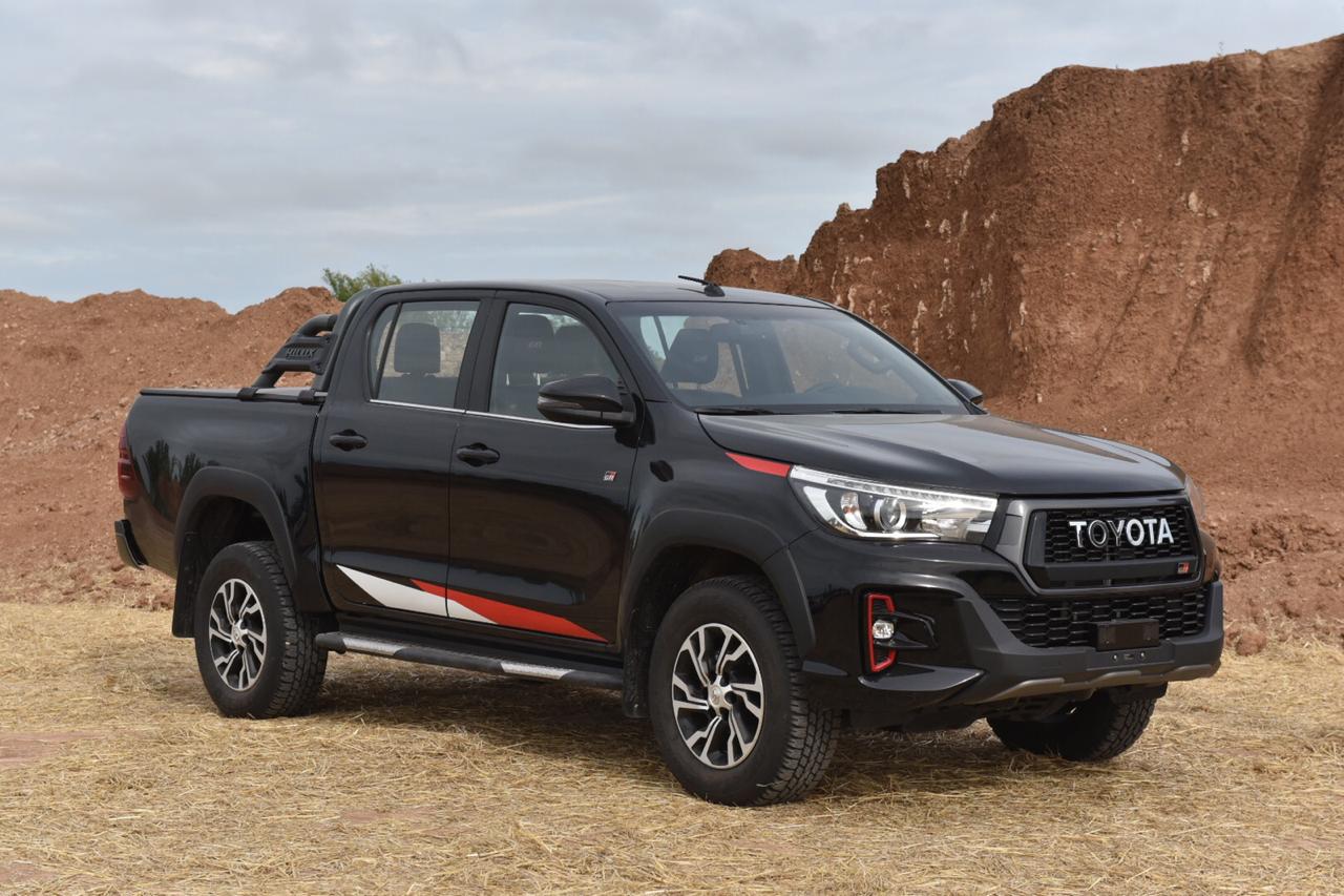 Toyota Hilux GR-S preta em um terreno arenoso parada na cor preta com detalhes discretos em branco e vermelho
