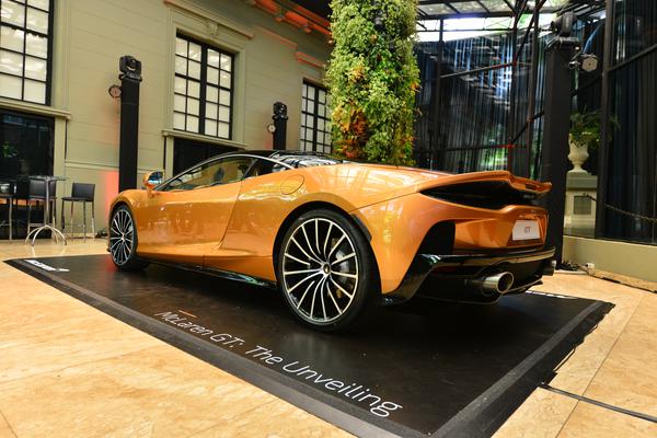 McLaren GT laranja em exposição em São Paulo, tem linha de cintura em cunha e traseira que se prolonga até formar um aerofólio acima das lanternas