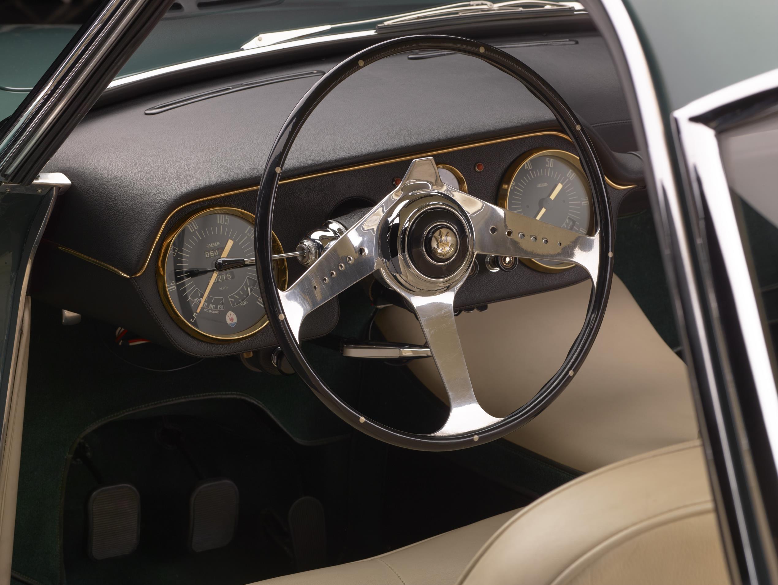 Cabine do Maserati mostra volante de aro fino com três raios cromados e mostradores de instrumentos circulares nas pontas do painel