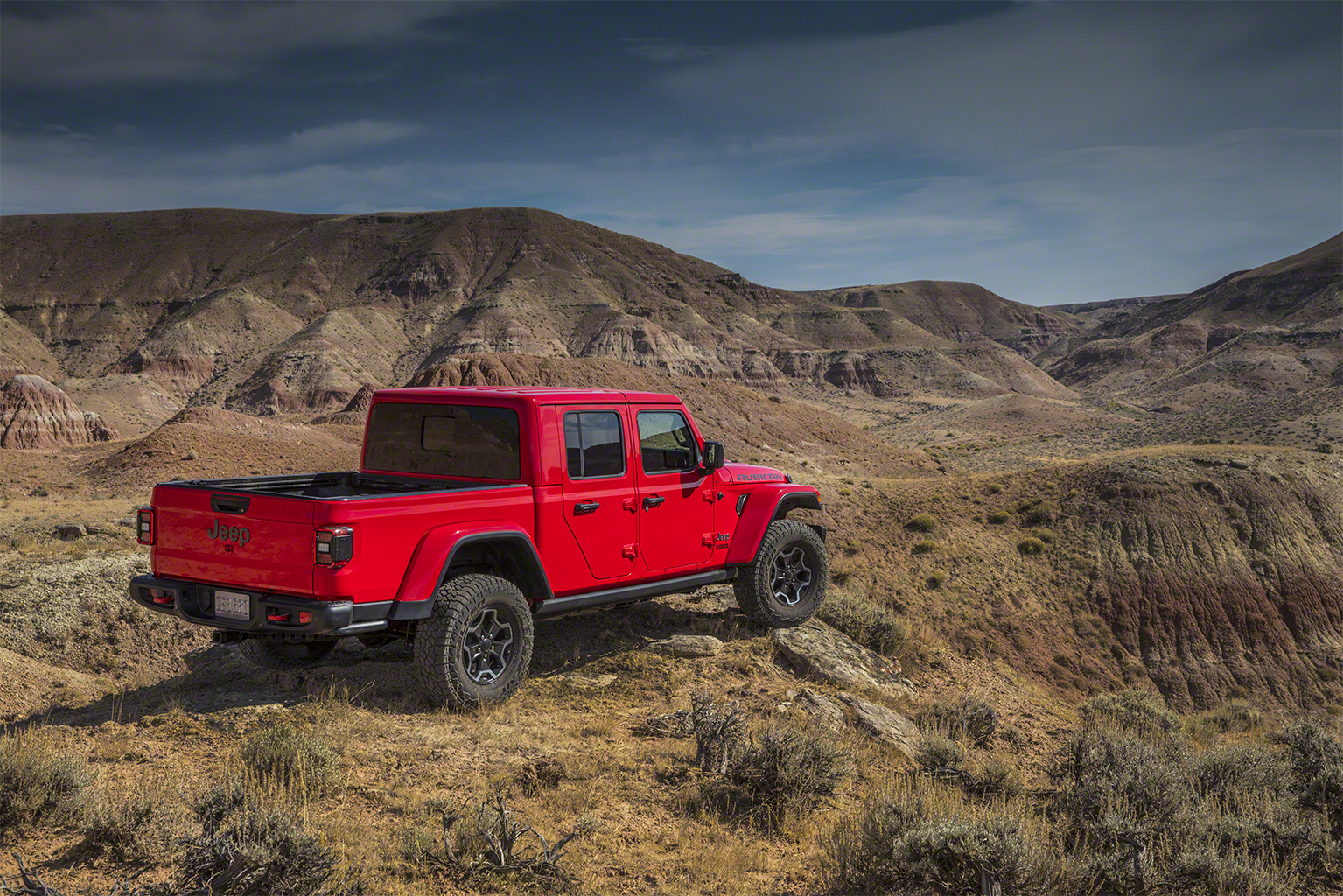 Jeep Gladiator na versão Rubicon e cor vermelha de traseira em uma paisagem de deserto