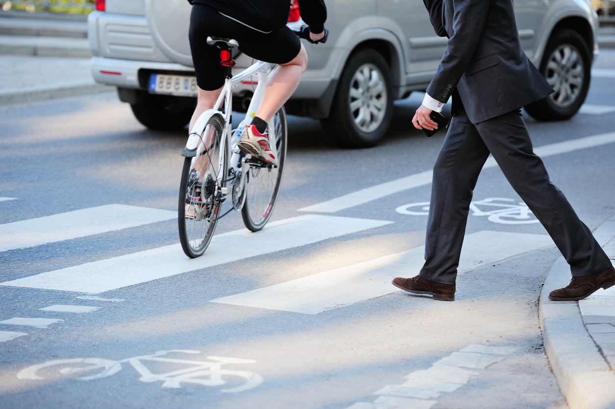 Bicicleta atravessa faixa de trânsito enquanto homem tenta atravessar a rua