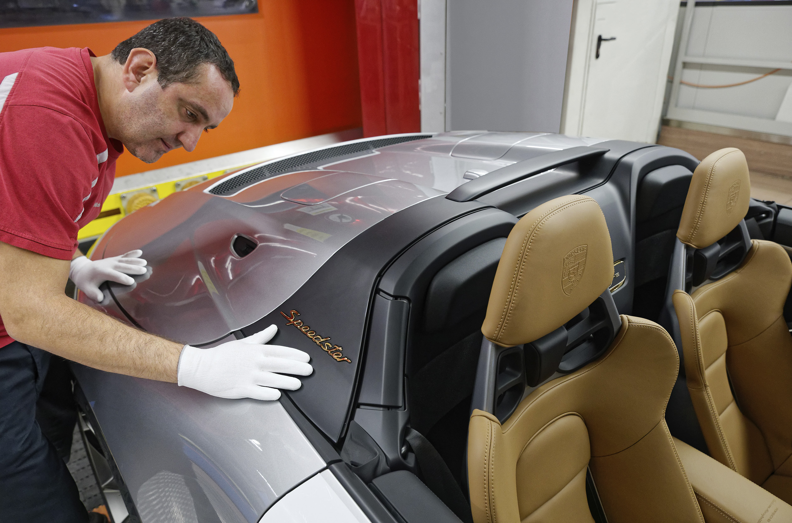 Homem na linha de produção da Porsche exanima, com luvas, a última versão Speedster da sétima geração do 911 a sair de fábrica
