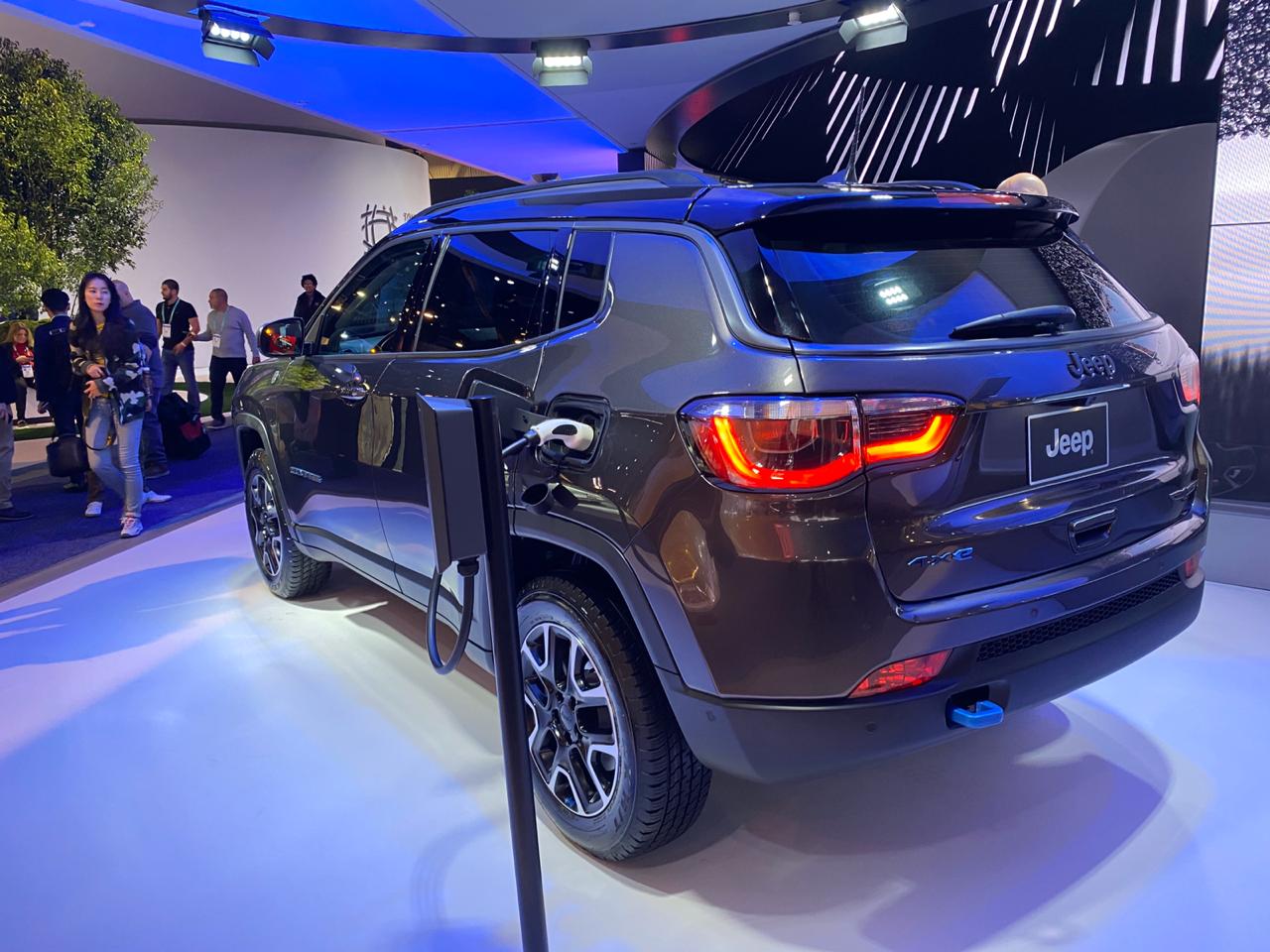Jeep Compass 4xe Híbrido Plug In sendo carregado na tomada em imagem de traseira no estande da Jeep na CES 2020, em Las Vegas