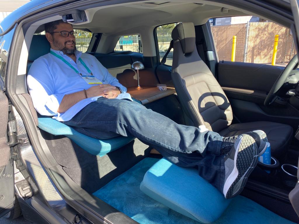 Jornalista sentado na poltrona traseira do i3 limousine e com os pés esticados e pousados no descansa-pé à frente