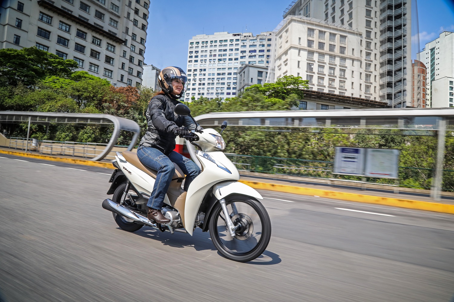 Mulher pilota Honda Biz 2020 em viaduto de São Paulo na cor branca com banco caramelo