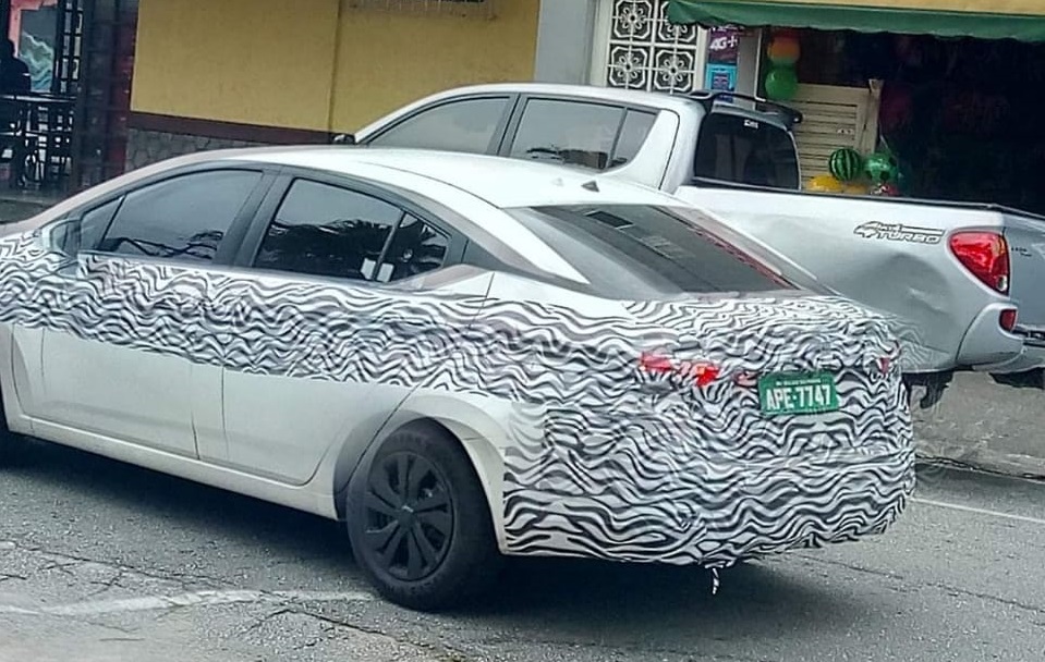 Novo Nissan Versa visto de traseira na cor branca e com camuflagem zebrada nas laterais e na tampa do porta-malas