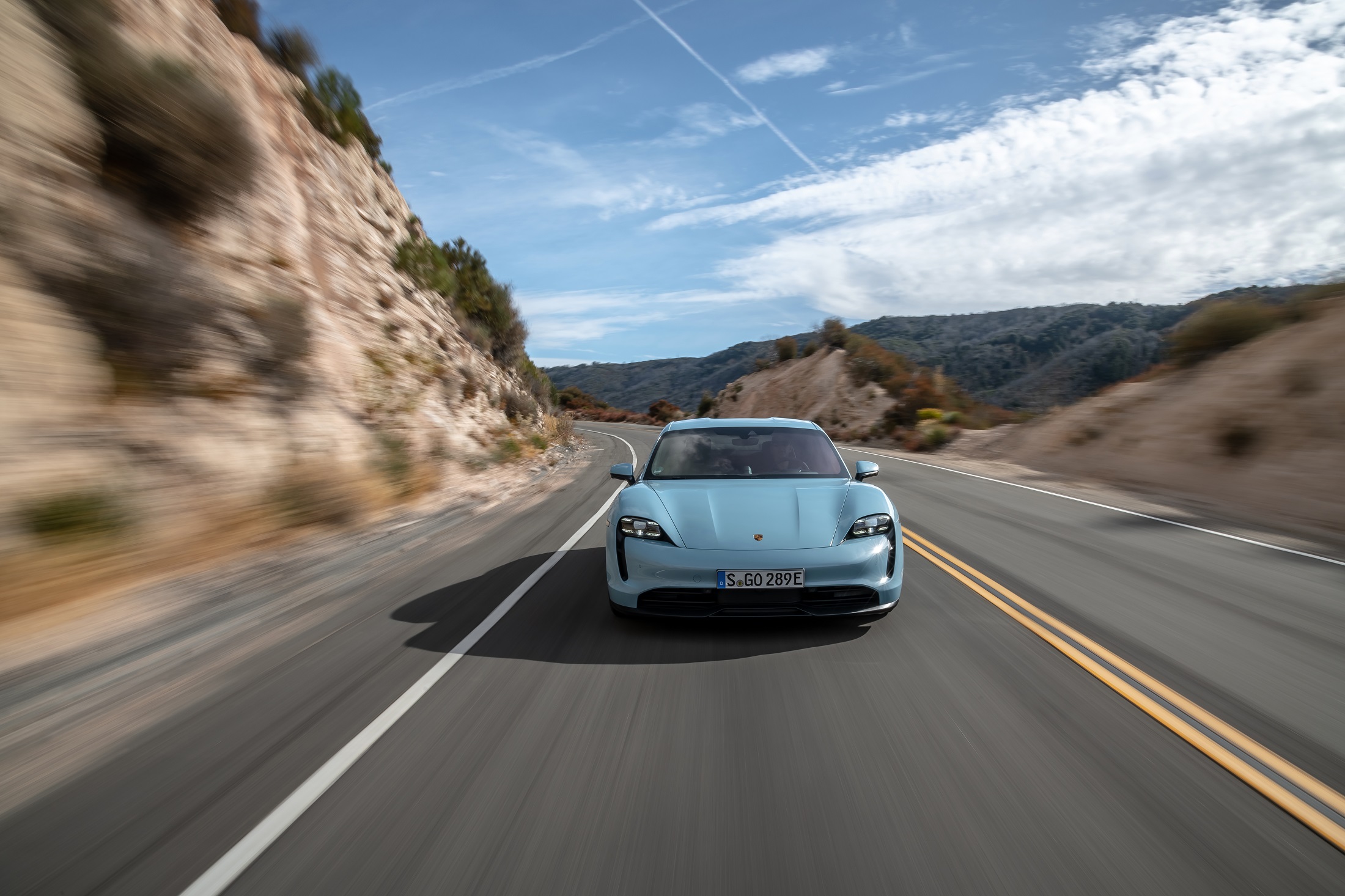 Porsche Taycan 4s na cor azul em movimento de frente na estrada