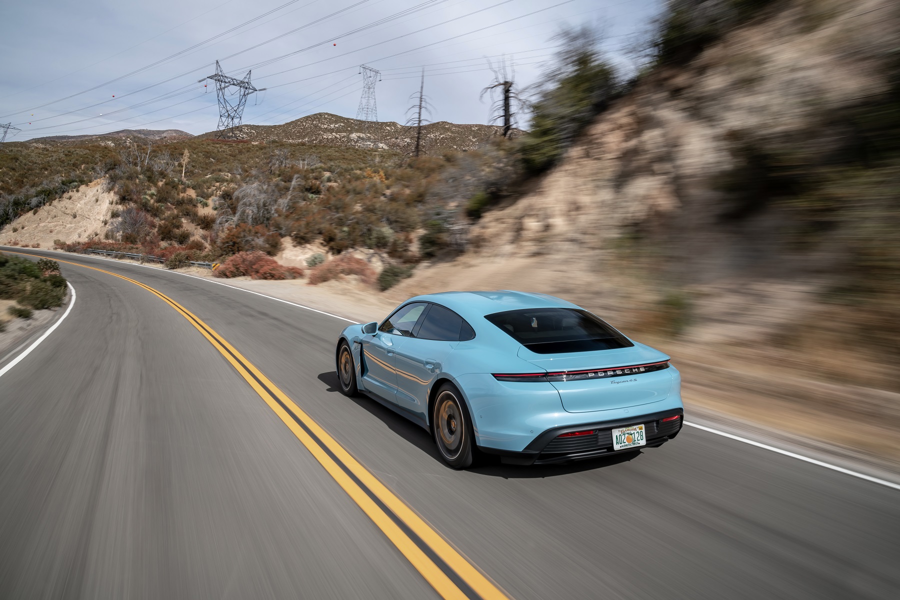 Porsche Taycan em movimento na cor azul de traseira