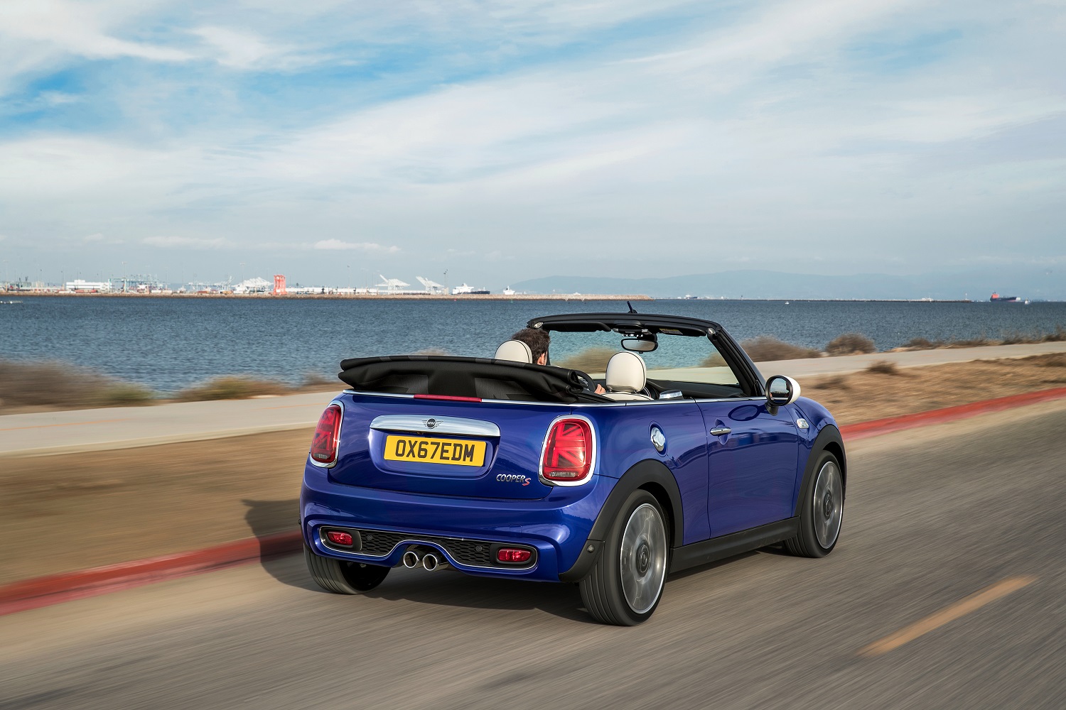 Mini Cooper Cabrio S na cor azul em movimento em estrada no litoral