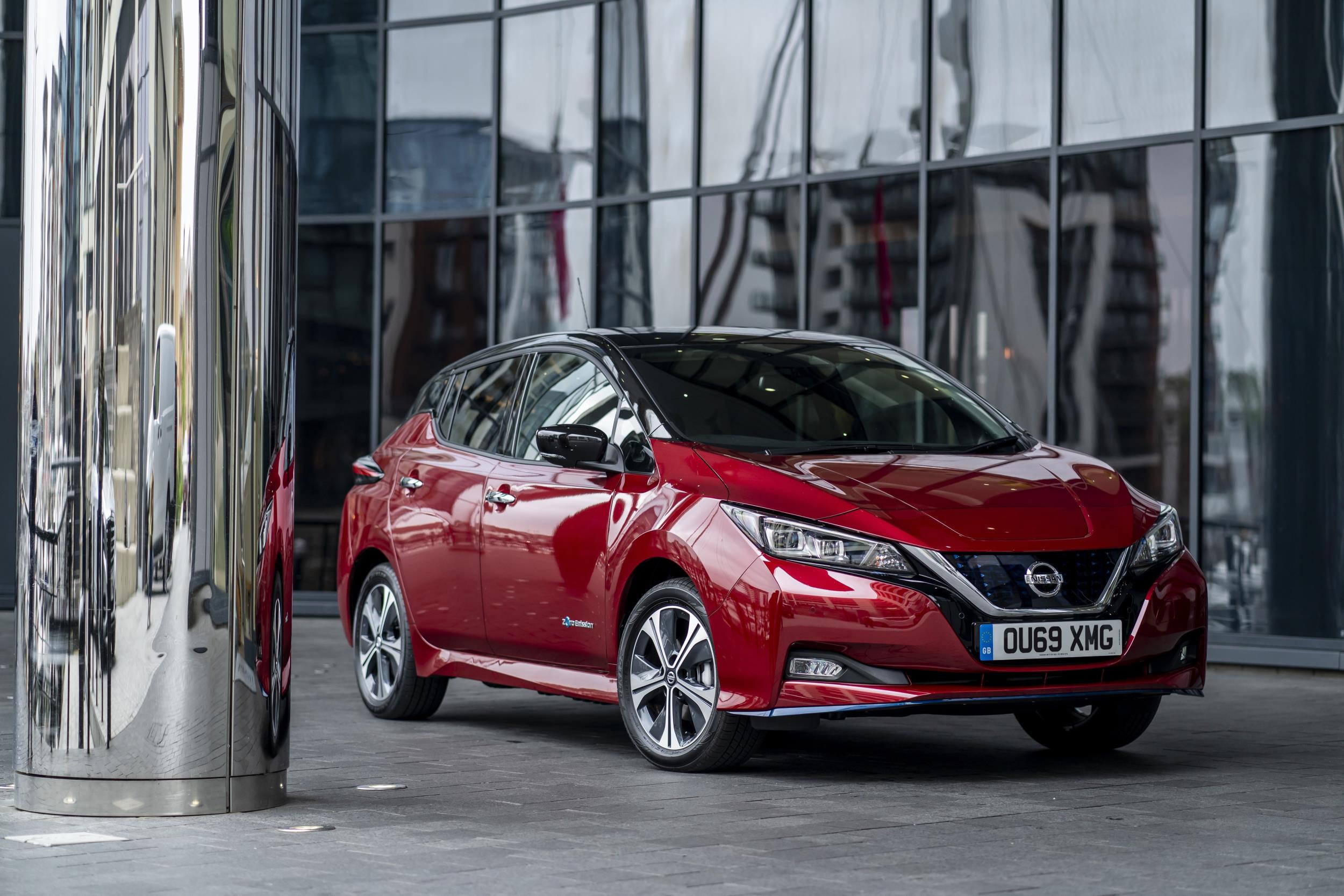 Nissan Leaf vermelho estacionado em frente a um prédio envidraçado