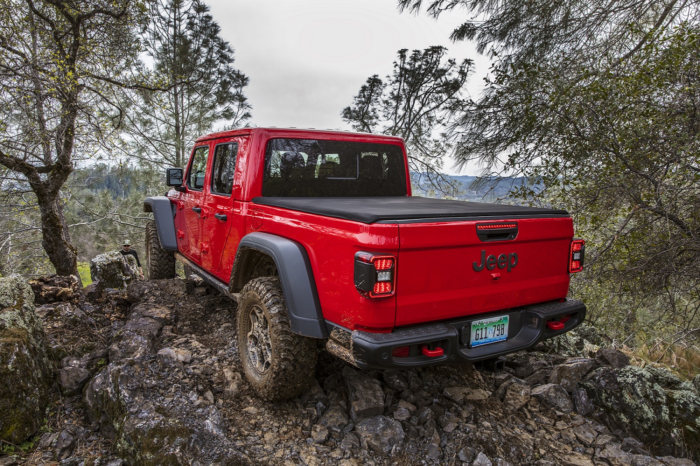 Jeep Gladiator Rubicon vermelha de traseira em trilha off-road de cascalho e pedra