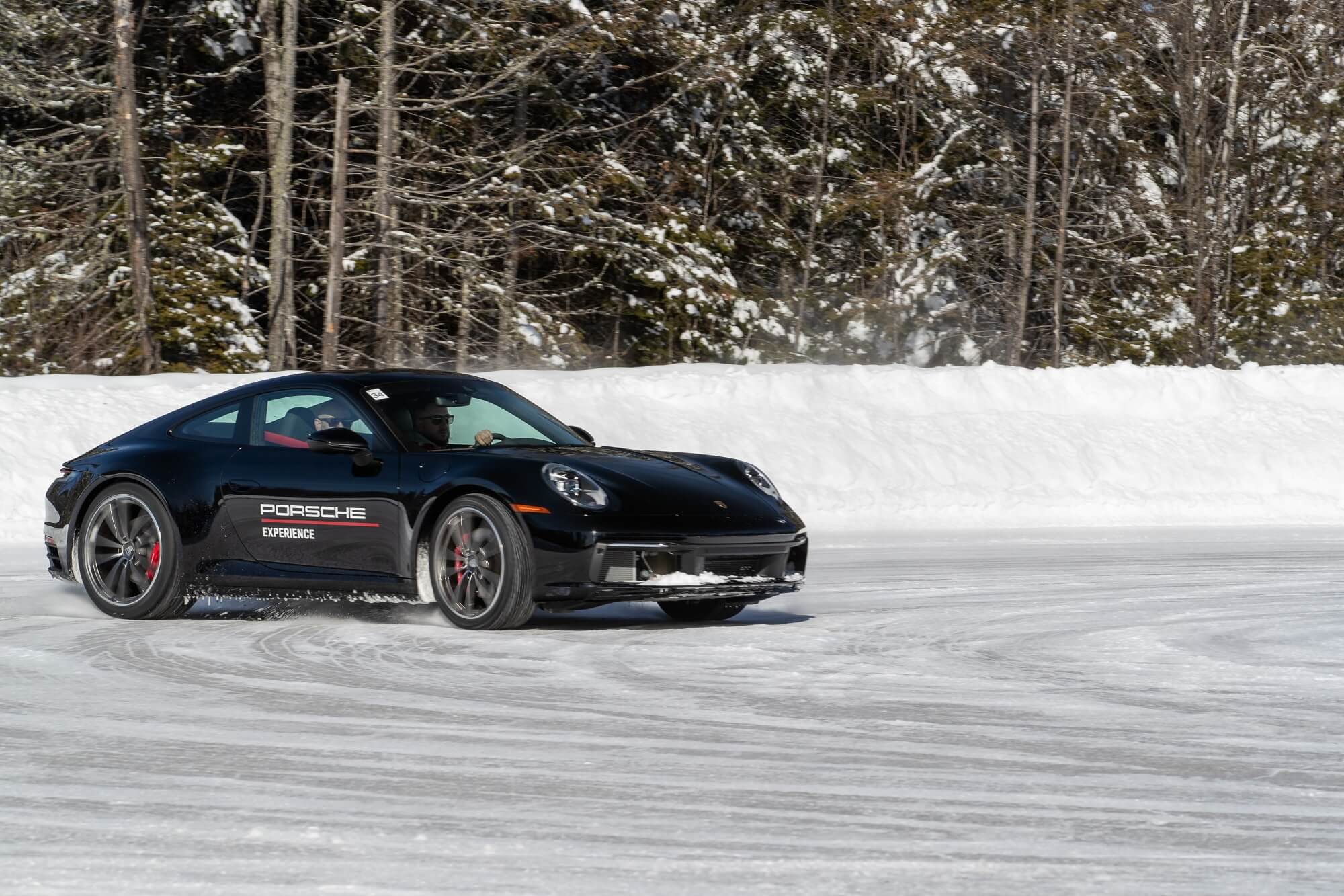 Porsche 911 preto derrapando na pista com as rodas dianteiras no sentido contrário ao da curva