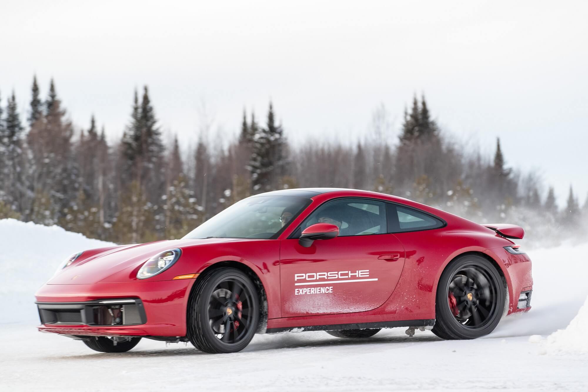 Porsche 911 vermelho levantando neve e gelo na traseira ao derrapar