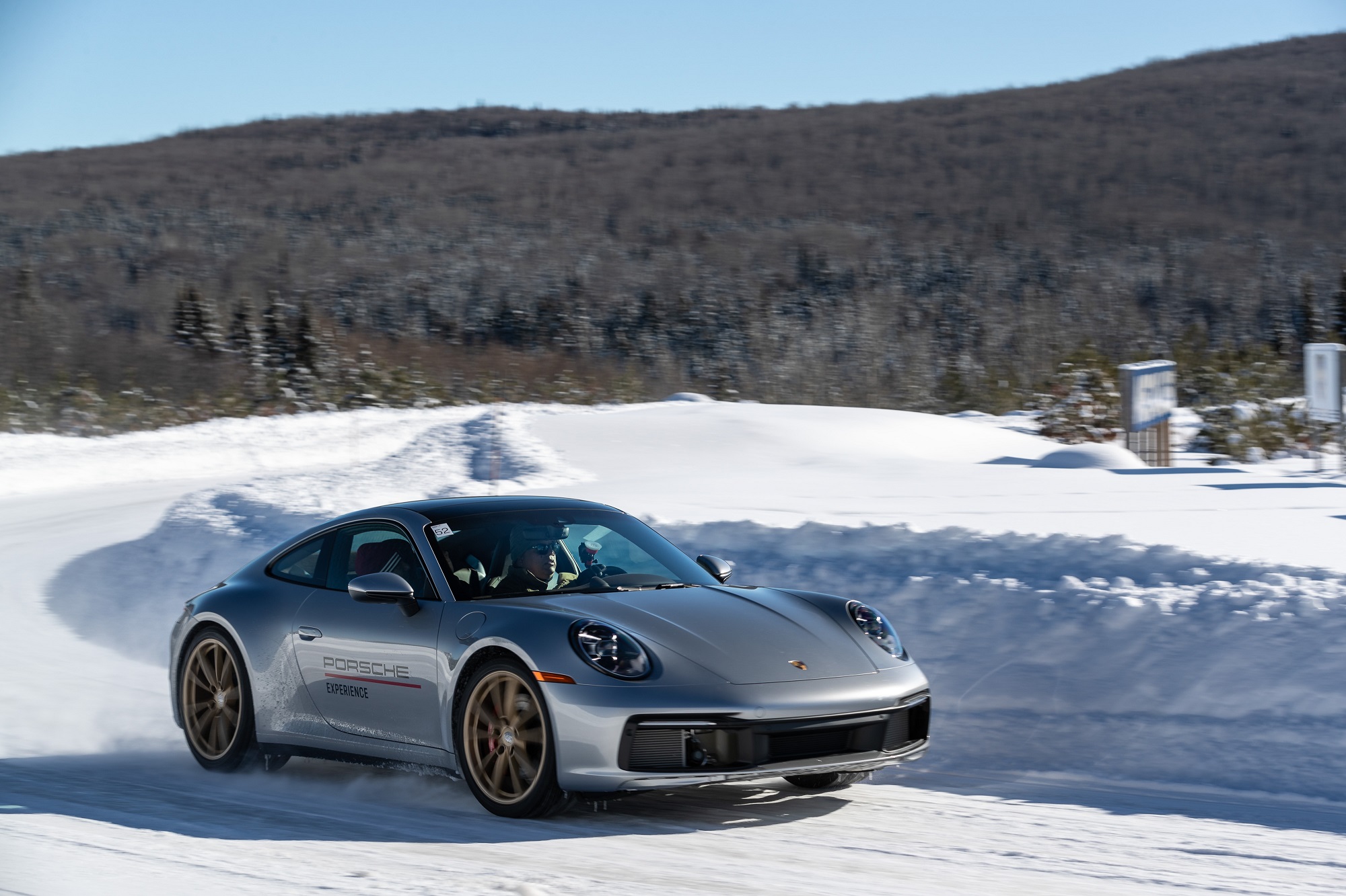 Porsche 911 prata na saída da curva em movimento na pista de neve