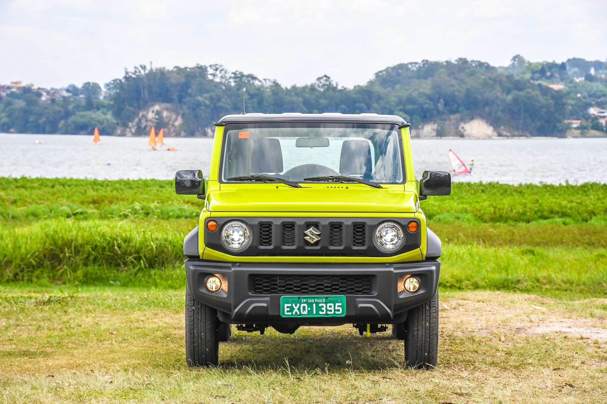Suzuki Jimny 4style na cor verde limão de frente em um terreno de terra e graama