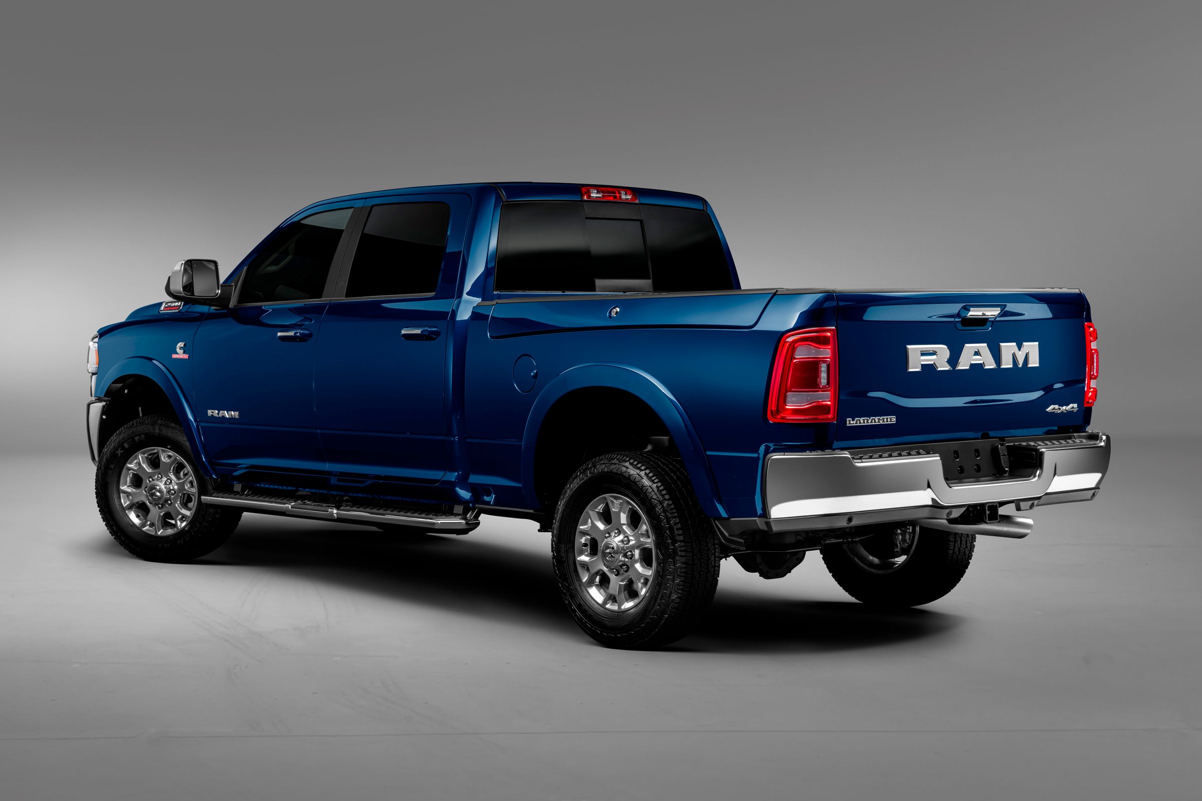 A picape azul em estúdio de traseira com para-choques na cor cinza e o enorme nome RAM na tampa da caçamba