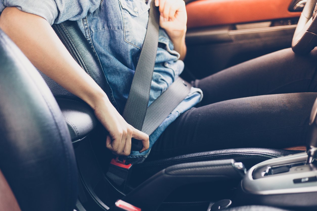 mulher no banco do motorista colocando o cinto de segurança