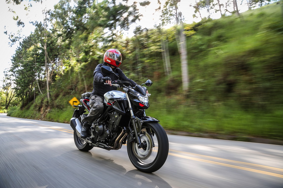 Honda Cb500f em movimento na estrada ao fundo árvores e mato