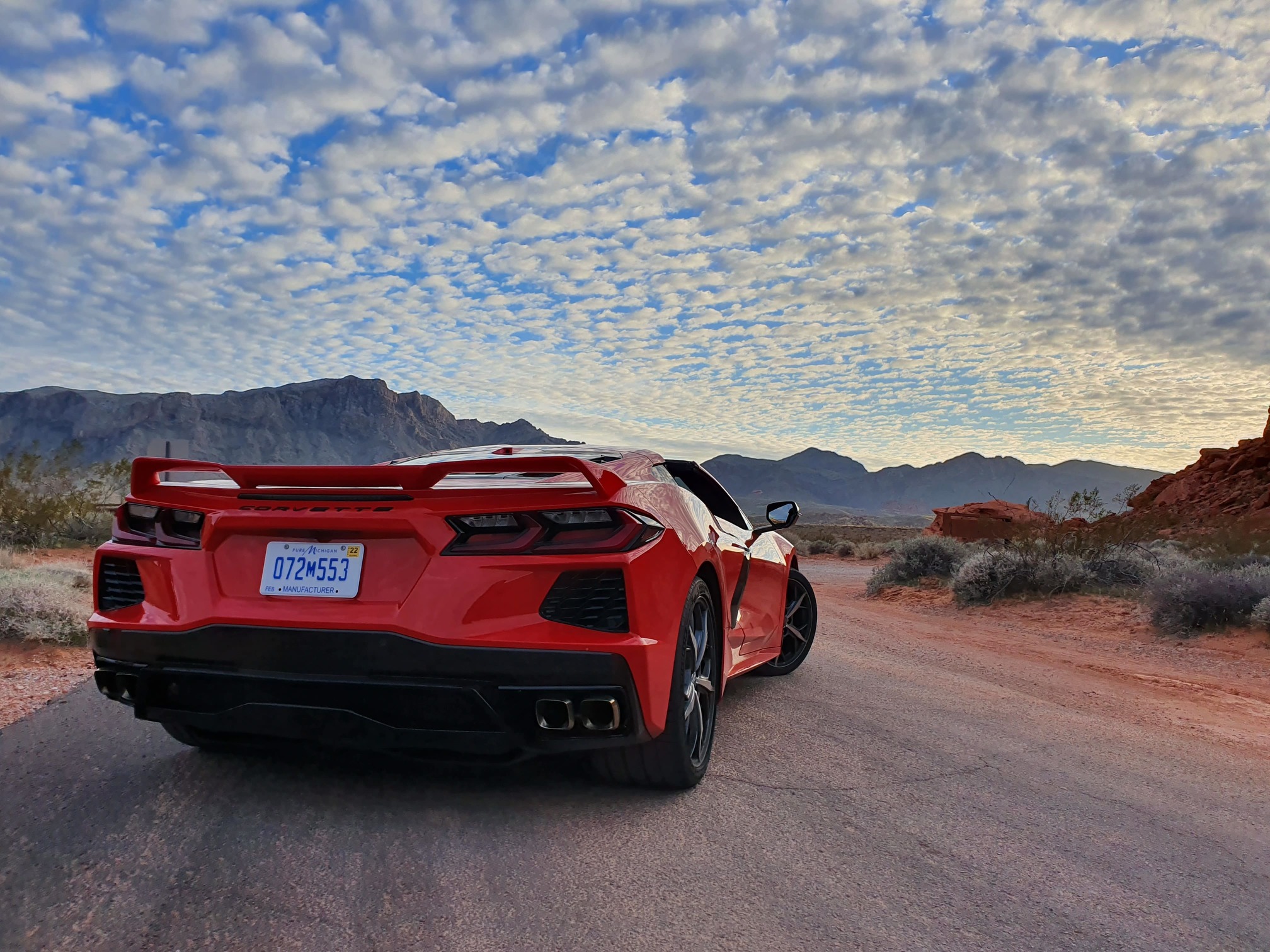 Chevrolet Corvette 2020 vermeho de traseira no deserto com um céu infinito com nuvens