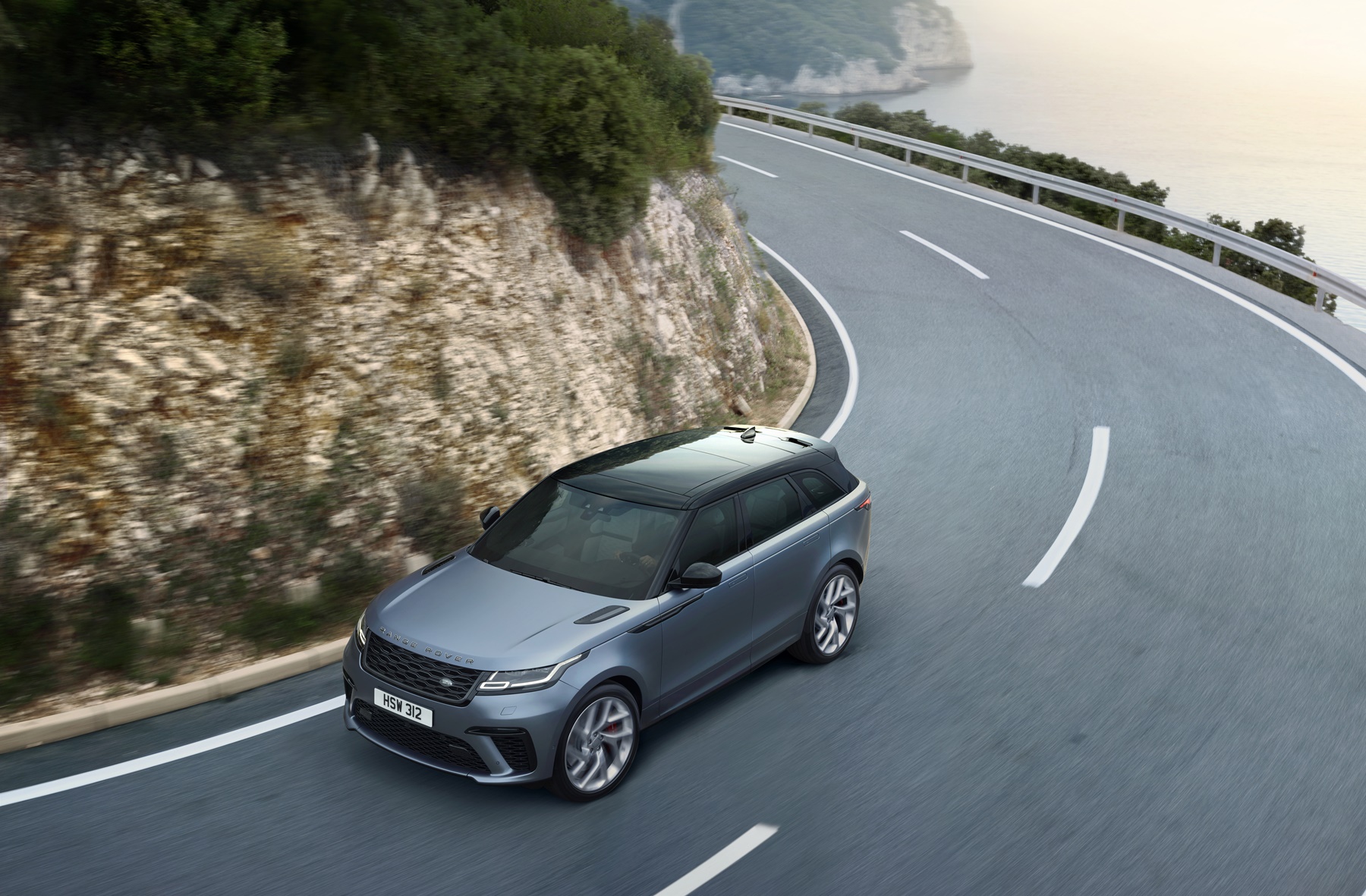 Range Rover Velar SV Autobiographyrafao de cima fazendo curva em uma estrada sinuosa com um morro de pedras
