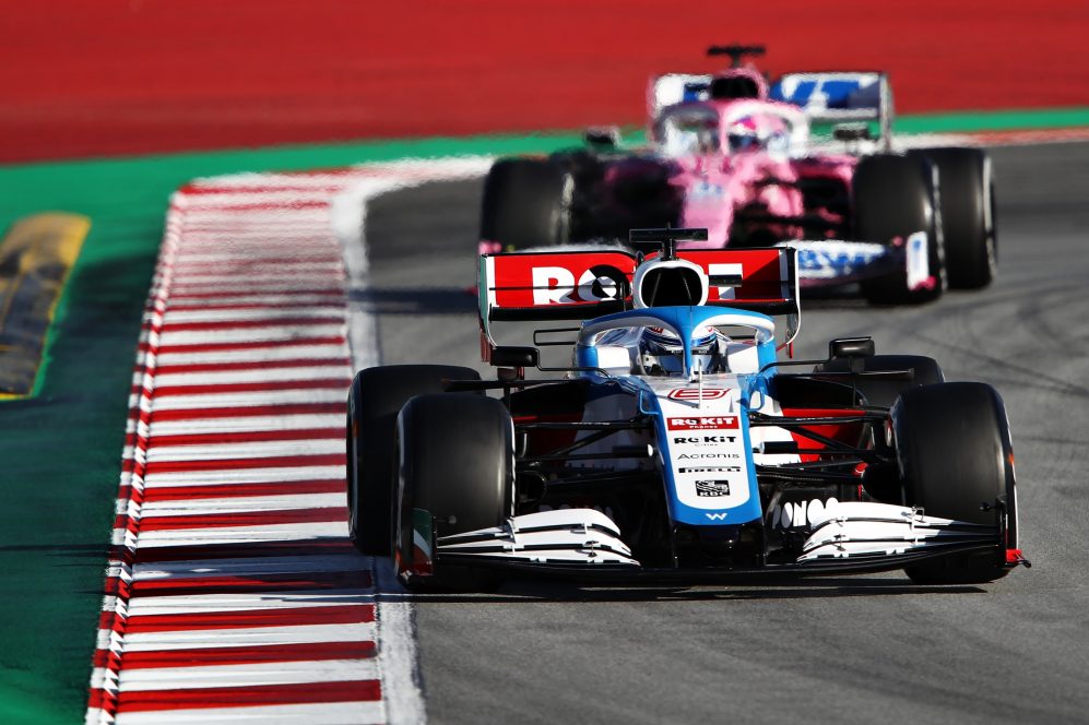 Williams Fw43 da Fórmula 1 em uma parte do circuito tendo ao fundo o carro rosa da Race Point
