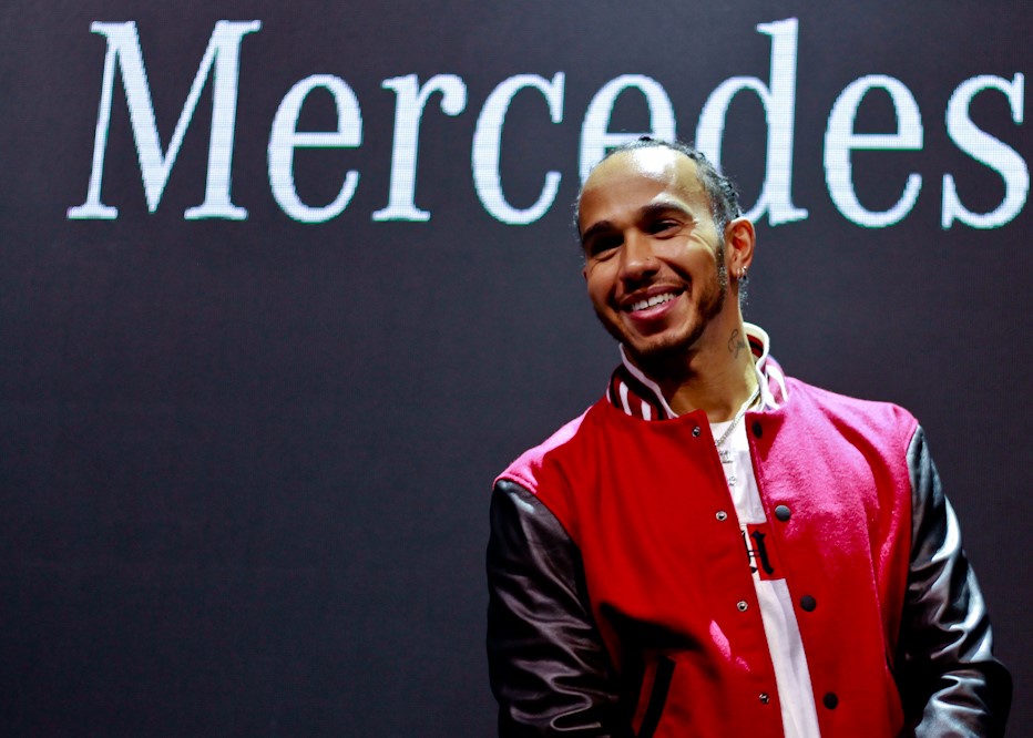 Lewis Hamilton, piloto da Mercedes, posa sorridente para a foto em um painel ao fundo com a palavra Mercedes