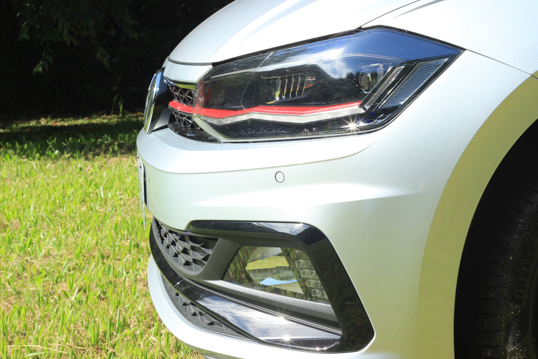 Imagem mostra farol de lado, com luzes de LEDs diferenciados , filete vermelho que nasce na ponta da grade e faróis de neblina com bordas retilíneas