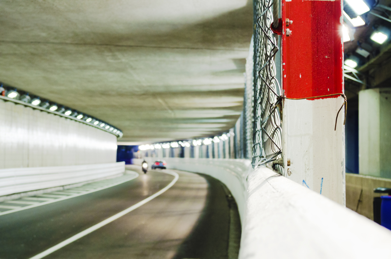 Imagem mostra o túnel do circuito de Monte Carlo com uma moto e um caro em movimento ao fundo e desfocdos