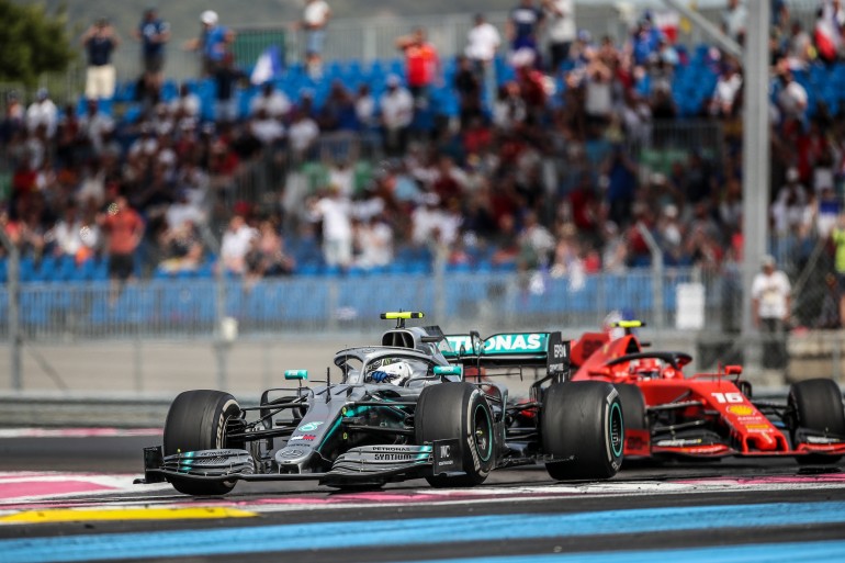 Carro de F1 da Mercedes faz a curva com carro da Ferrari colado durante prova da Fórmula 1