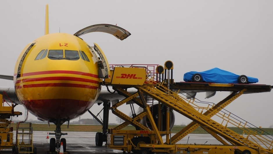 Carro de Fórmula 1 coberta embarca em avião de carga amarelo da DHL