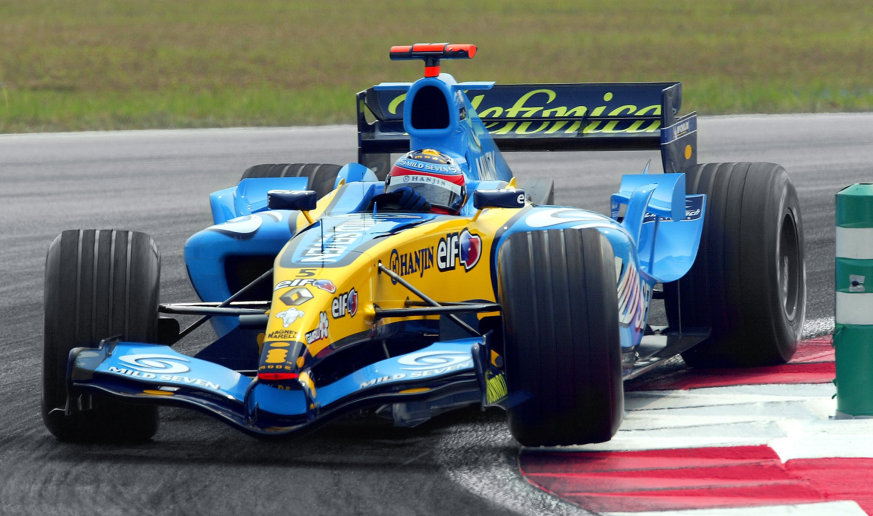 Caro de Fórmula 1 da Renault pilotado por Fernando Alonso F1 faz uma curva com as rodas da esquerda sobre a zebra