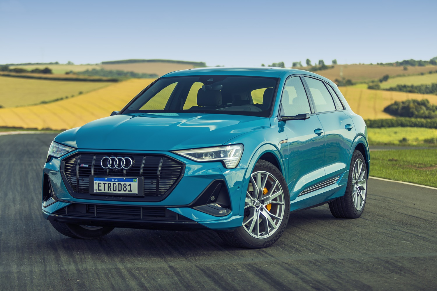 Audi E Tron azul de frente com gramado verde claro ao fundo