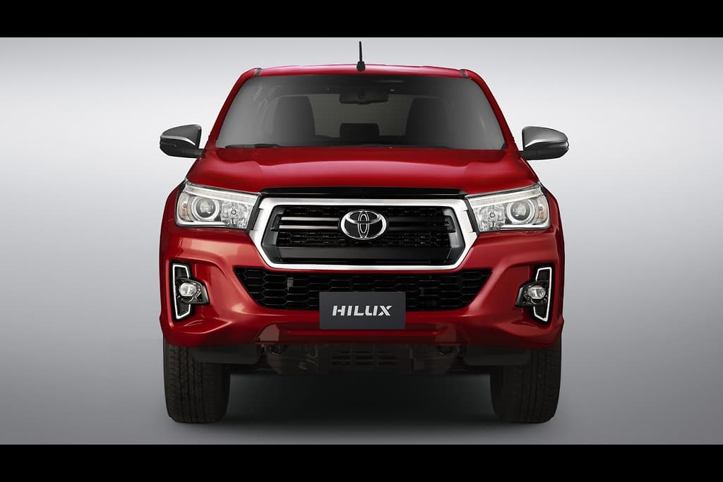 Projeção mostra uma Toyota Hilux 2021 na cor vermelha de frente com grade mais estreita e novas entradas de ar