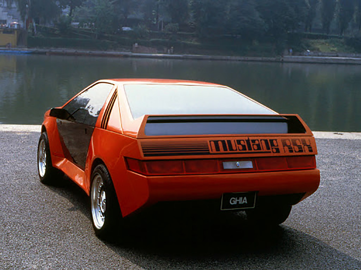 Ford Mustang Rsx Ghia laranja de traseira com aerofólio reto destacado e lanternas inteiriças que se prolongam até as laterais