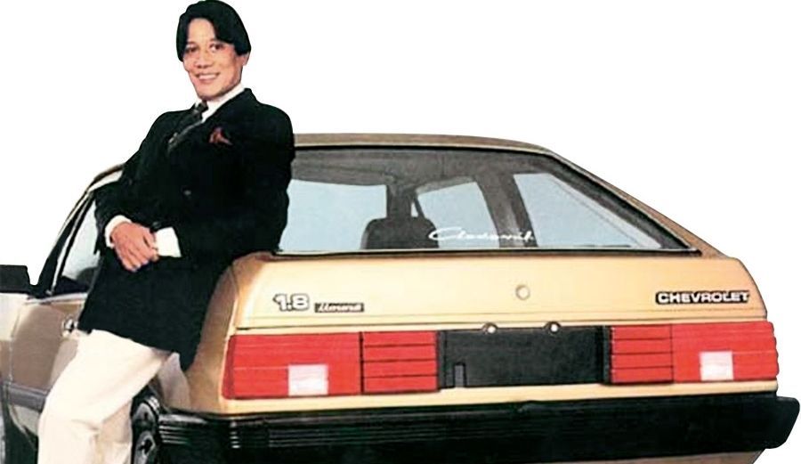 Monza Clodovil bege e estilista sentado na lateral