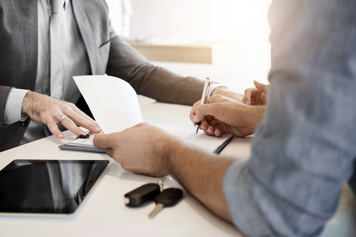 Homem assina documentação para comprar um veículo