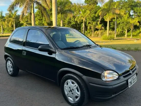 Imagem de um Chevrolet Corsa preto em bom estado localizado em uma rua com árvores de fundo, ideal para quem busca carro barato até 15 mil reais.