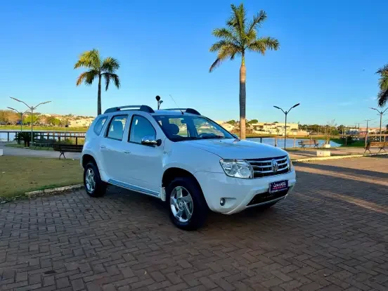 Imagem de um Renault Duster branco estacionado em um parque com árvores, céu azul e lago ao fundo, ideal para quem busca um SUV confiável até 50 mil reais.