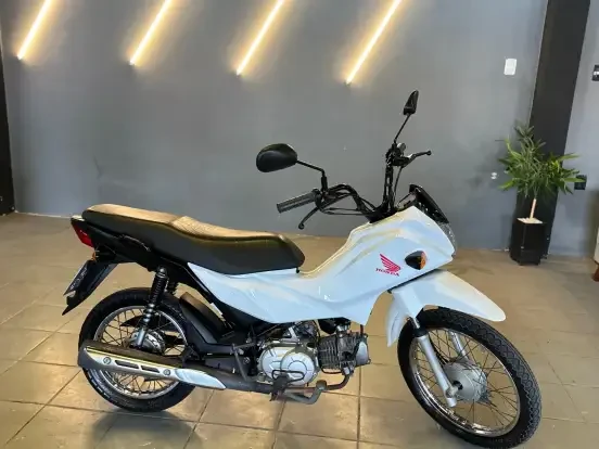 Imagem de uma Honda Pop 110i na cor branca, em excelente estado, em destaque na loja, ideal para quem busca uma moto econômica até 18 mil reais.